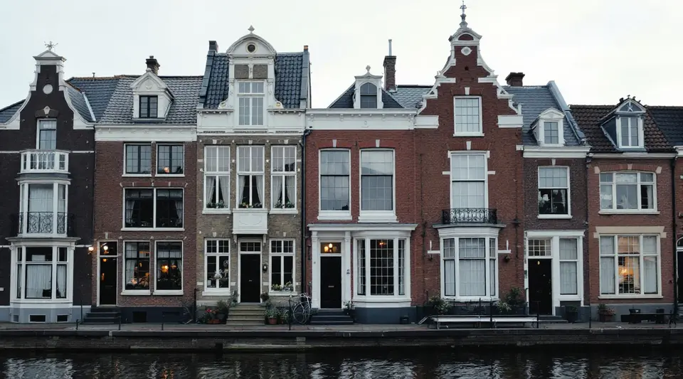 Historische grachtenpanden met witte houten schuiframen en kleine ruitjes aan het water